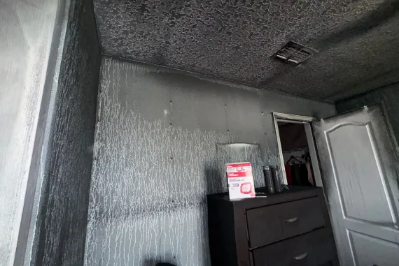 Bedroom with smoke-stained walls and streaked surfaces